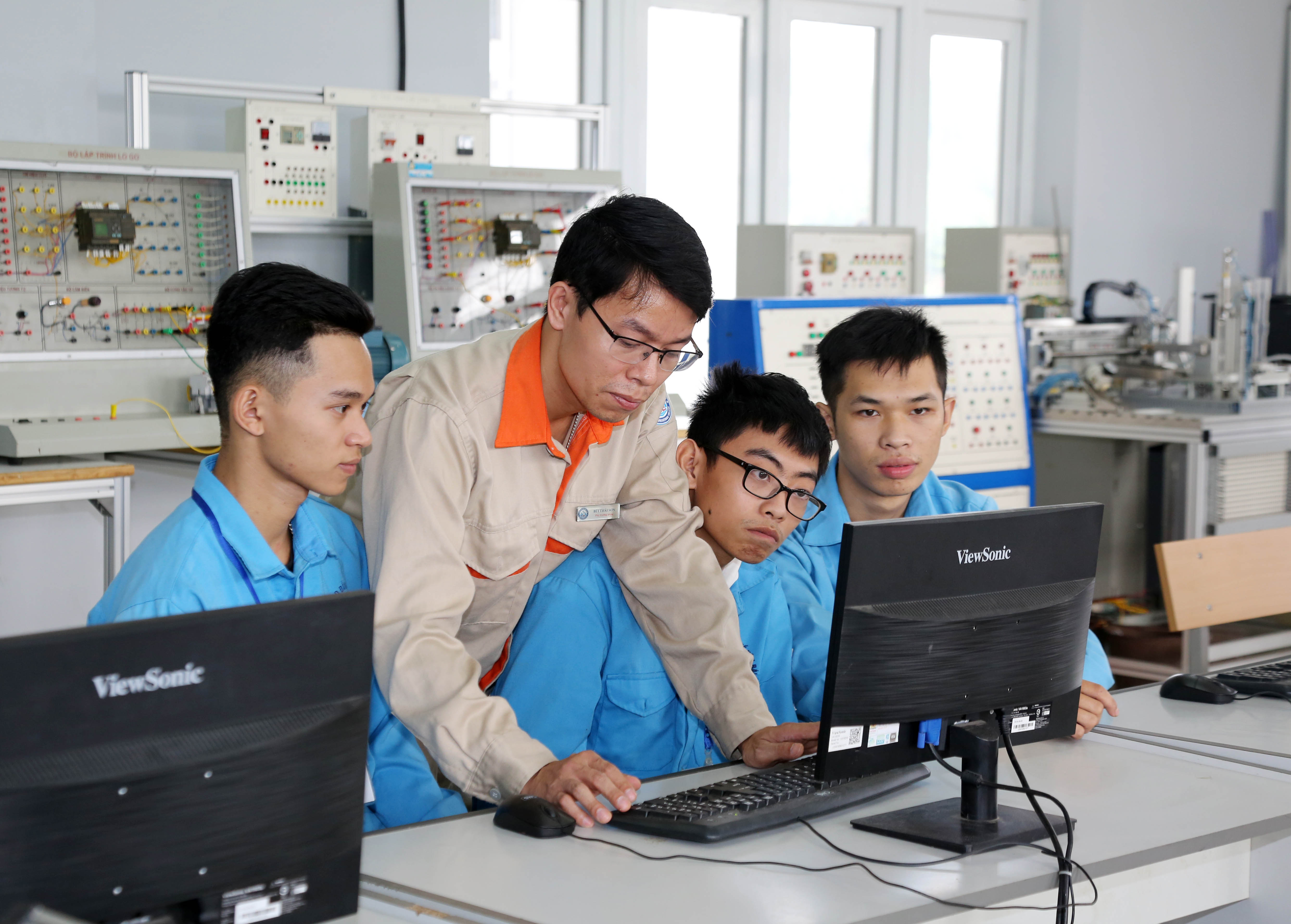 Thầy Bùi Thái Sơn (đứng giữa) hướng dẫn các em lớp Điện Công nghiệp thực hành trên máy tính 
